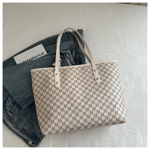 Detail of monogram M print on white leather tote with metallic rivet reinforcements