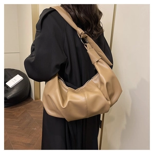 Close-up of khaki pleated dumpling bag with knot handle and large metal ring detail