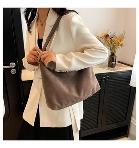 Dettaglio della borsa tote in pelle scamosciata marrone scuro indossata con blazer bianco