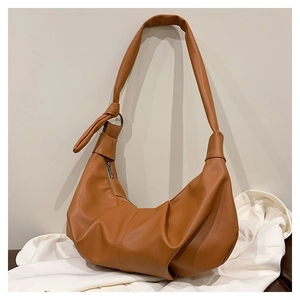 Detail view of brown dumpling bag with ruched base and decorative knot on strap
