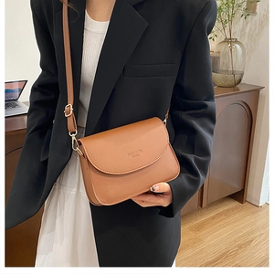Détail d'un sac bandoulière en cuir caramel avec sangle réglable et texte embossé