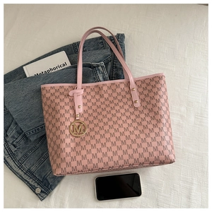 Detail shot of pink quilted tote bag with letter M pattern and metal logo charm decoration
