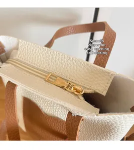 Close-up of smooth golden metal zipper and pebble grain texture on two-tone tote bag