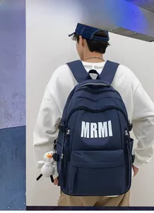 Detail view of navy blue nylon backpack featuring white MRMI lettering and a plush duck toy