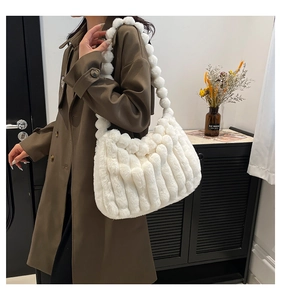 Detail of white plush tote bag with unique spherical strap on brown autumn coat