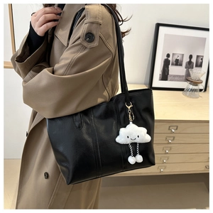 Detail einer schwarzen Shopper-Tasche aus Kunstleder mit süßem Wolken-Plüsch-Anhänger
