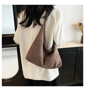 Borsa tote in pelle scamosciata marrone indossata da modella con blazer bianco