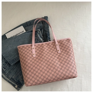 Detail of pink tote bag with M letter prints and gold rivets on white fabric