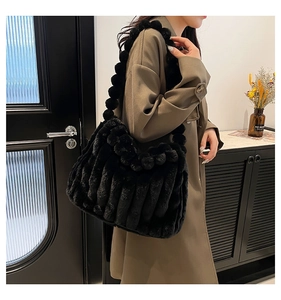 Detail of black plush tote bag featuring textured faux fur and pom-pom ball decorations