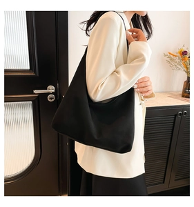 Vista laterale di una grande borsa tote nera opaca indossata da una modella in casa
