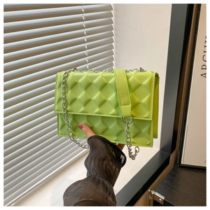 Detail of neon green quilted crossbody bag with 3D geometric texture and silver chain strap