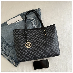 Flat lay of tote bag featuring gray M letter pattern and gold logo pendant detail