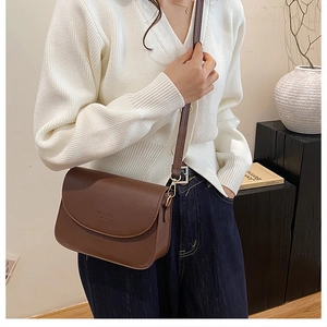 Détail d'un sac bandoulière marron avec texte FASHION BAGS et détails métalliques dorés