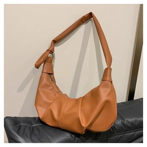 Detail of caramel pleated crescent bag showing premium lychee texture and knot strap