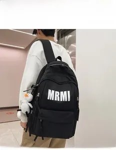 Detailed view of large black nylon backpack with MRMI logo and white duck pendant