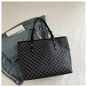 Detailed view of black tote bag with gray M letter patterns and gold rivets