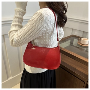 Detailed close-up of glossy red patent leather baguette bag with premium gold zipper