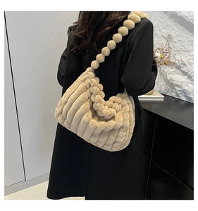 Detail view of beige plush tote bag featuring soft pleated texture and decorative faux fur pom-poms