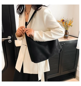 Dettaglio di una grande borsa hobo nera opaca con tracolla larga per pendolari d'ufficio