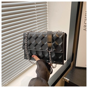 Detailed close-up of black quilted shoulder bag with silver metal chain strap