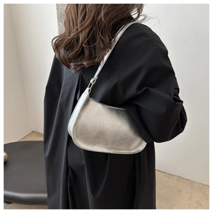 Chic silver metallic crescent underarm bag with natural textured finish shown on shoulder