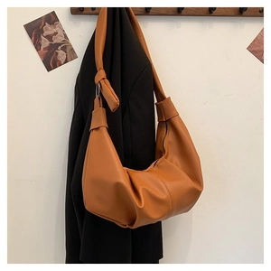 Detail of caramel leather shoulder bag with knotted strap and textured pebble grain finish