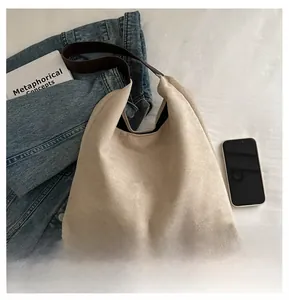 Detail of large beige suede tote bag with brown shoulder strap in a lifestyle setting