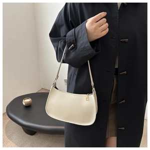 Detail view of cream leather shoulder bag with gold zipper and minimalist strap
