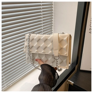 Detail of white quilted crossbody bag with silver chain and 3D textured faux leather
