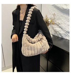 Detail view of beige plush tote bag with vertical stripes and fuzzy pom-pom shoulder strap