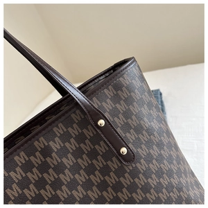 Detail of classic brown monogram M pattern and polished leather edges on tote bag