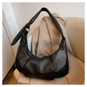 Detail of black lychee-textured leather shoulder bag with pleated design and knot strap