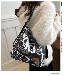 Detail of graffiti-style crossbody bag showing adjustable strap and metal buckle fasteners