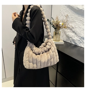 Detail of beige faux fur tote bag showing textured vertical stripes and plush ball strap