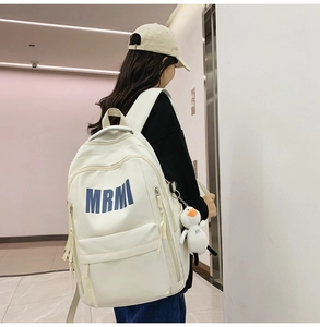 Detail view of white MRMI backpack with cute duck pendant and durable canvas texture