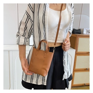 Detail of lychee pattern brown leather mini tote bag with adjustable crossbody strap