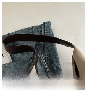 Detailed view of the dark brown leather handle on a large ivory tote bag for women
