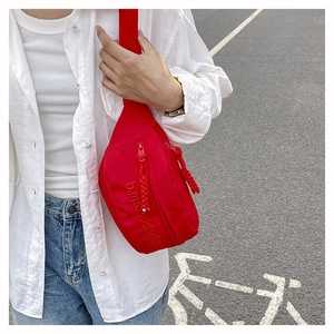 Détail du sac banane de sport rouge vif en nylon avec broderie et large bandoulière