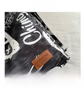 Detail of black canvas bag with white graffiti print and brown leather brand label