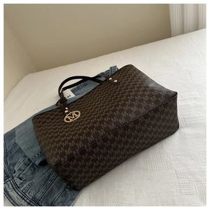 Detail of the brown monogram tote bag with leather straps and golden M-letter charm