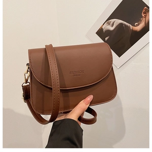 Détail du sac à bandoulière en cuir marron avec texte embossé et finitions métalliques dorées
