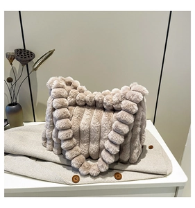 Close-up of beige plush tote bag with vertical stripe texture and fluffy ball details