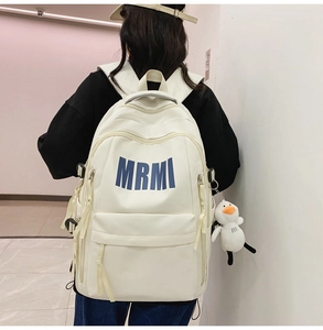 Detail of white minimalist backpack with MRMI text and cute duck plush charm