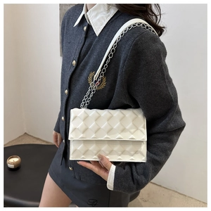 Detail of white quilted handbag with 3D embossed texture and silver chain strap on model