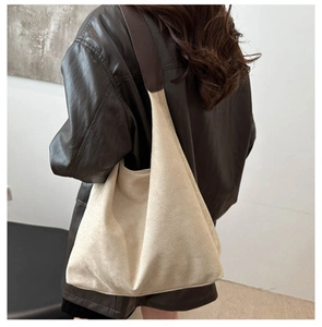 Detail view of cream canvas tote bag with brown leather straps worn on shoulder