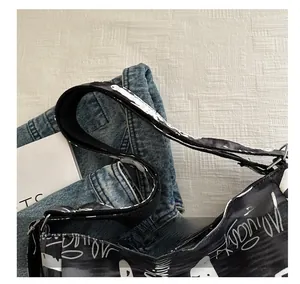 Close-up detail of wide canvas shoulder strap and graffiti pattern on large tote bag