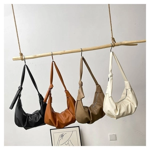 Row of pleated hobo bags in black, caramel, khaki, and cream hanging on a wooden rod