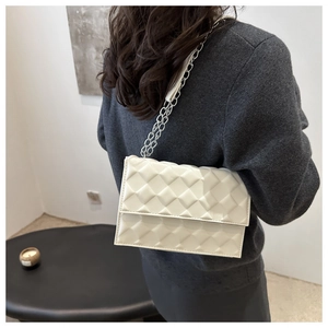 Detailed view of white quilted faux leather flap bag with silver chain strap on model