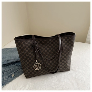 Detailed close-up of brown monogram tote bag with a metallic M pendant and long straps