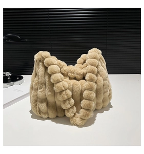 Detail of soft fuzzy tote bag featuring vertical ribbed texture and plush pom pom strap